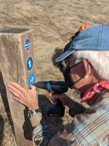 person installing ridge trail signs on sign post