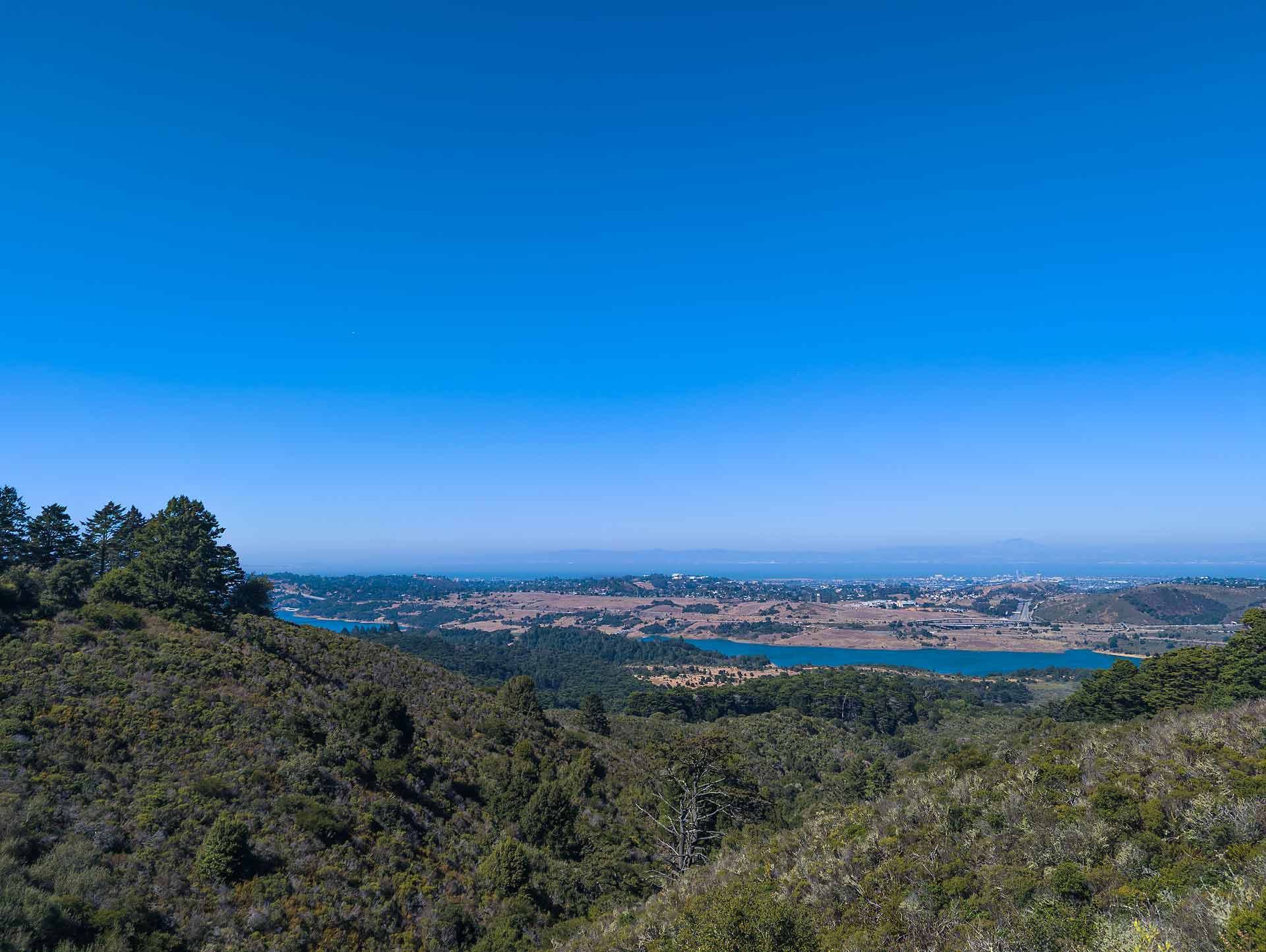 an expansive view of distant hills and a reservoir behind rolling green hills